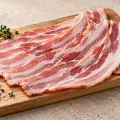 Tranches de bacon fumé cru disposées sur une planche