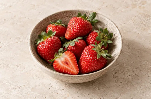 Fraises rouges fraîches entières et coupées dans un bol en grès
