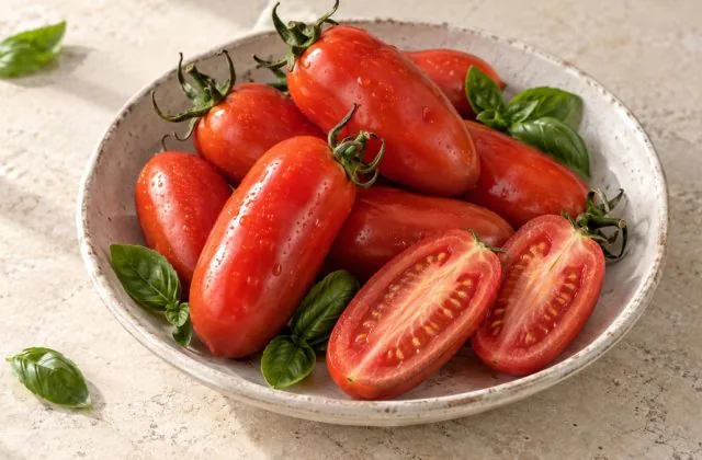 Tomates San Marzano entières et coupées dans un plat en grès