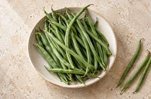 Haricots verts frais et fins dans une assiette en grès