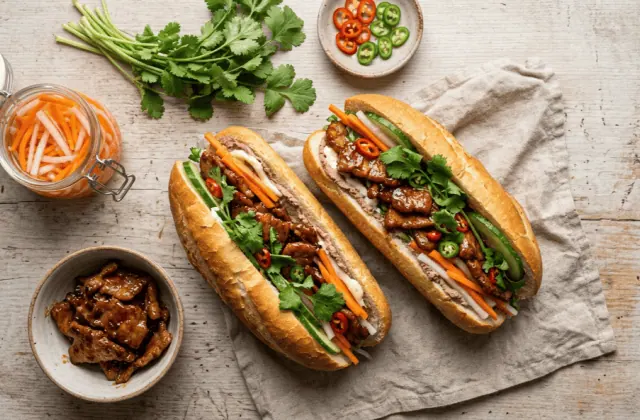 Bánh mì maison au porc caramélisé et pickles, avec bocal de pickles, coriandre et piments