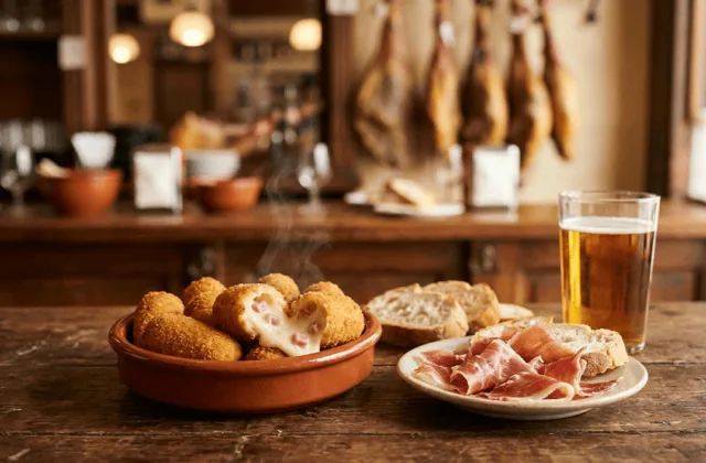 Croquetas de jamón dans une cazuela en terre cuite, l’une ouverte sur sa béchamel crémeuse au jambon, dans un bar à tapas