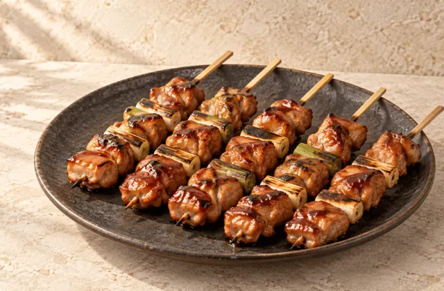 Yakitori de poulet et poireau laqués sur une assiette japonaise