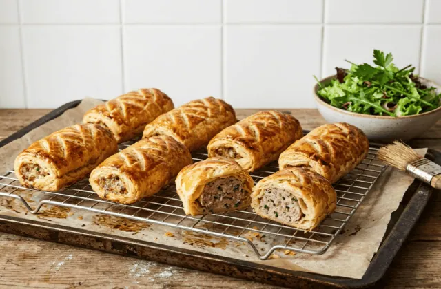 Friands à la viande maison dorés sur une grille, l’un coupé montrant la farce, salade verte à côté