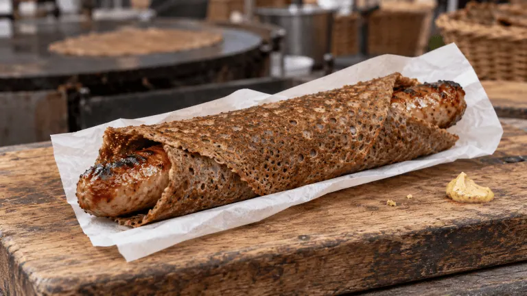 Galette-saucisse bretonne servie dans un papier sur un marché