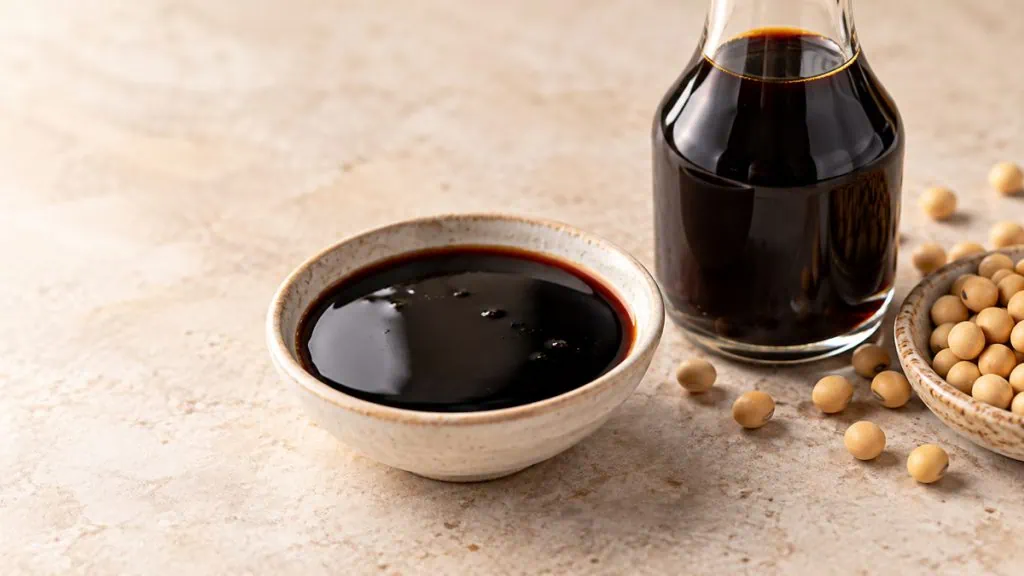 Kecap manis sombre et sirupeux dans une coupelle avec bouteille neutre