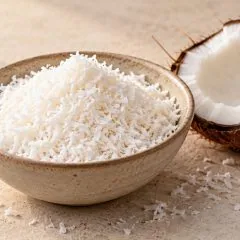 Noix de coco râpée dans un bol avec une demi-noix de coco