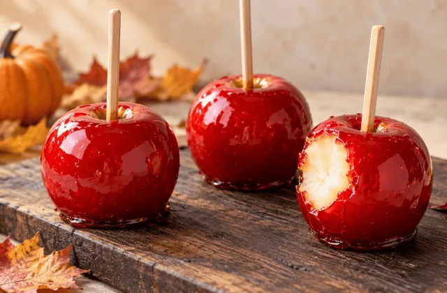 Pommes d’amour brillantes au caramel rouge sur bâtonnets, dont une croquée