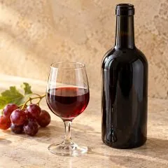 Verre de porto rouge accompagné d’une bouteille sombre