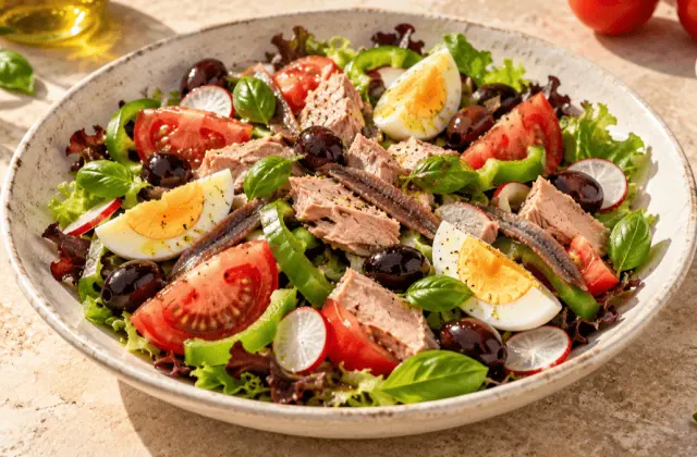 Salade niçoise avec tomate, thon, œuf dur, anchois, olives noires, poivron et basilic