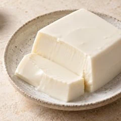 Bloc de tofu soyeux blanc dans une assiette en grès clair