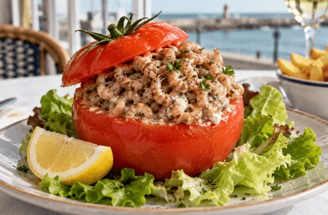 Tomate-crevettes belge garnie de crevettes grises, servie avec salade, citron et frites